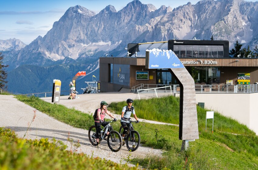Two mountain bikers at Flowline start near Planai top station at 1830 m, with Dachstein range rising in the background | © Planai-Hochwurzen-Bahnen GesmbH